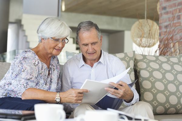 Older couple reading papers together on sofa