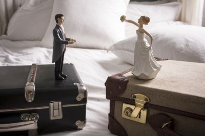 bride and groom figurines on separate luggage