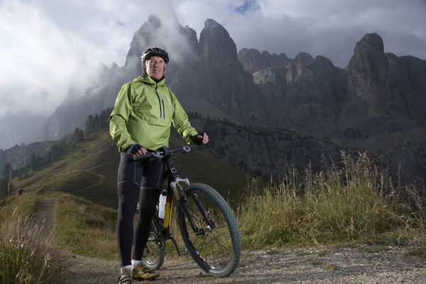 Man with a bike in front of a mountain.