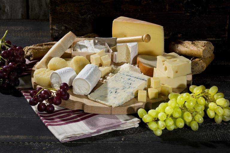 platter with different sorts of cheese, baguette and grapes on