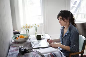 young woman writing at a laptop