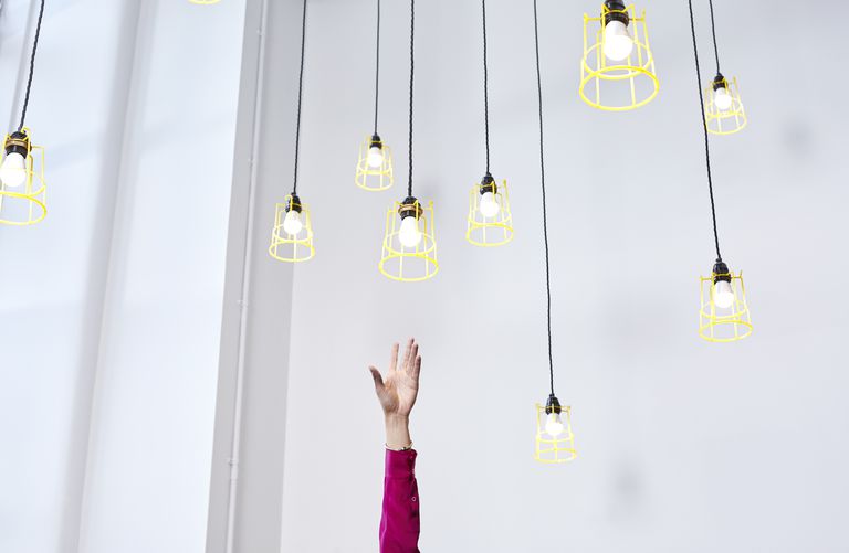 hand reaching for hanging light bulbs