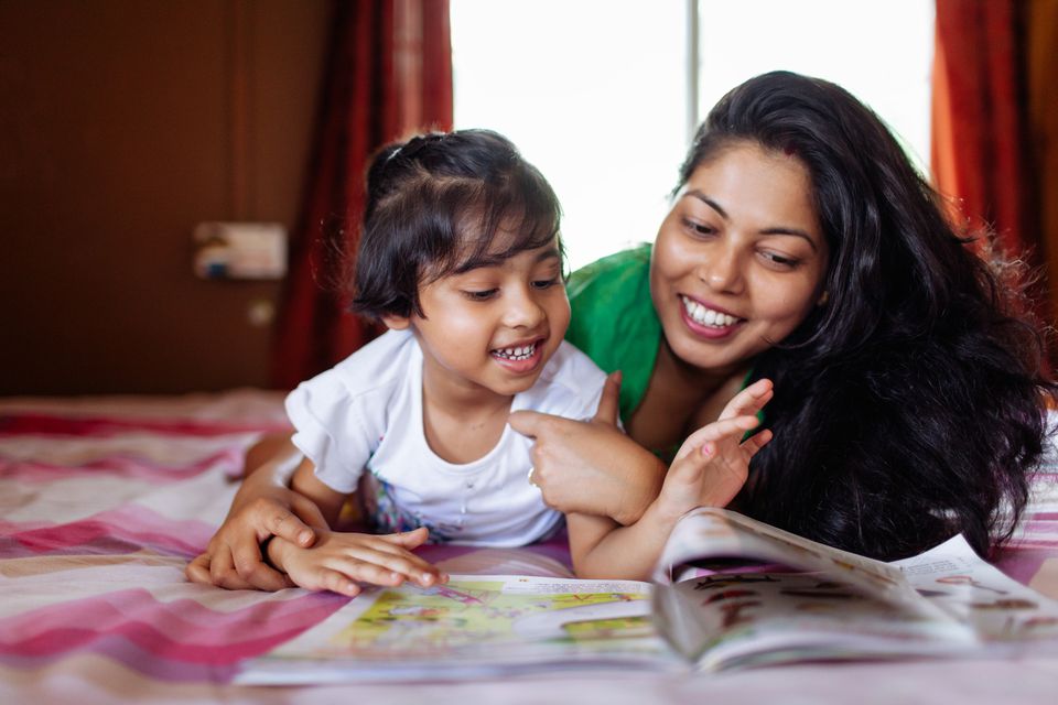 Mother reading book with daughter