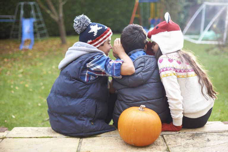 Children whispering on Halloween.