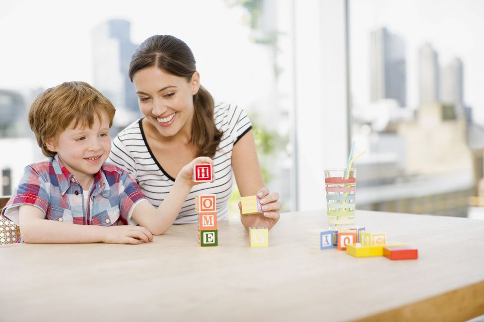 A picture of a mom and child playing a learning game with blocks