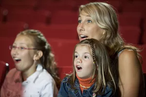 Mother and daughters sitting in theatre seats