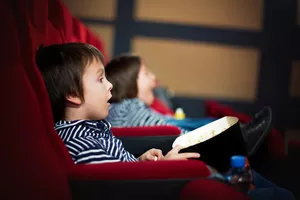 Two preschool children, twin brothers, watching movie in the cinema