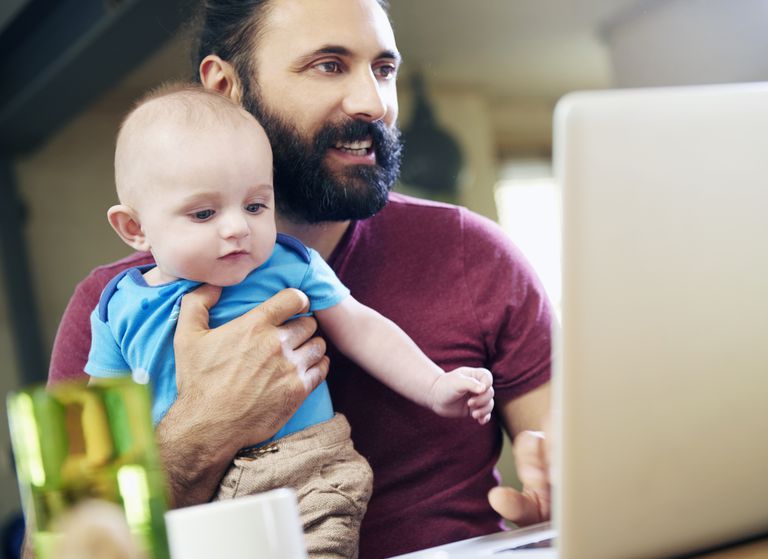 Father with baby working on laptop at home