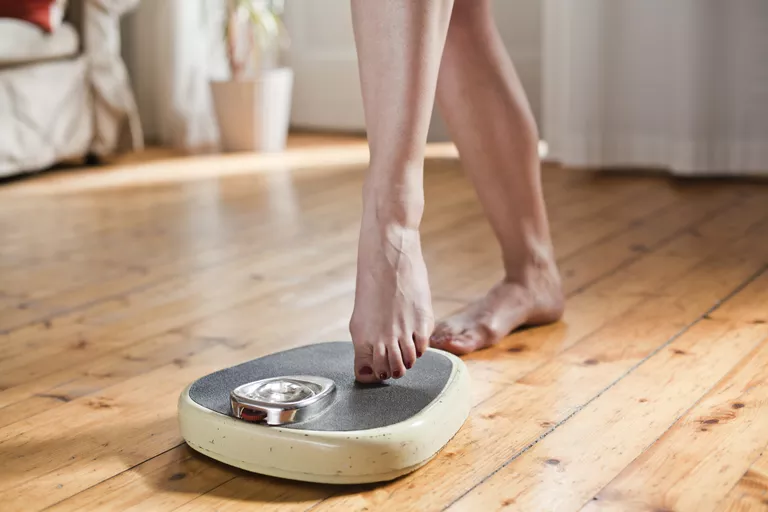 woman stepping on scale with toe to weigh herself