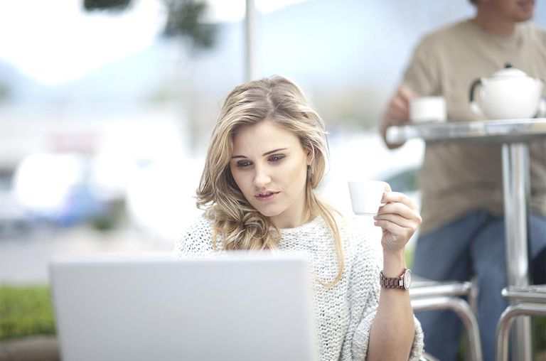 Young woman at cafe with coffee, using laptop