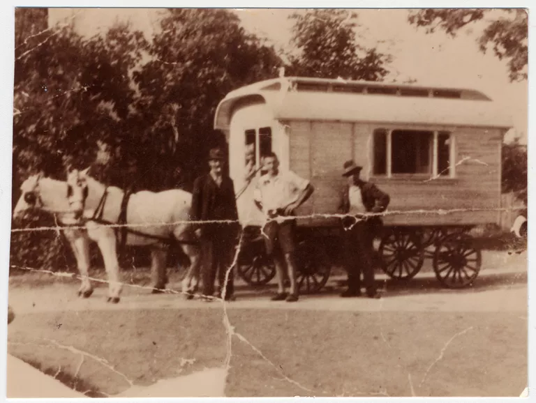 Three Gypsies pose in front of a horse-drawn caravan.