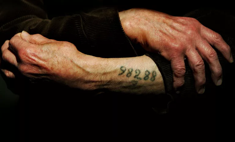 A Holocaust survivor showing his tattooed number.