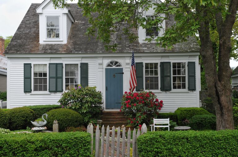 white cape cod style house with shutters, dormers, and fanlight