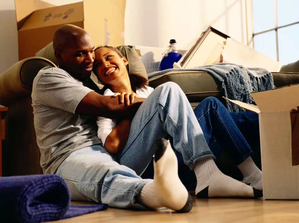 Happy couple sitting on floor with unpacked moving boxes