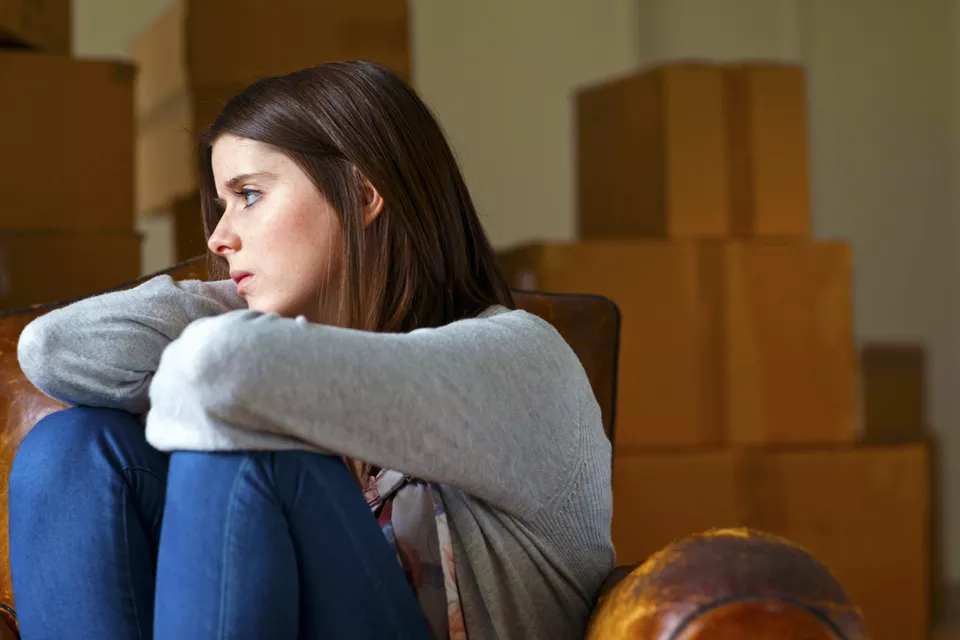 Sad woman surrounded by packed moving boxes