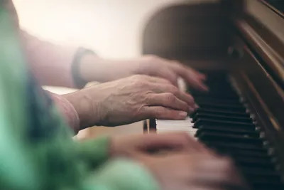 Side view of senior woman and girls hands playing piano together