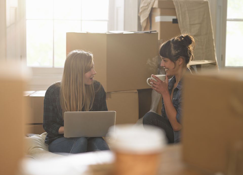 Two women in new apartment looking at a laptop