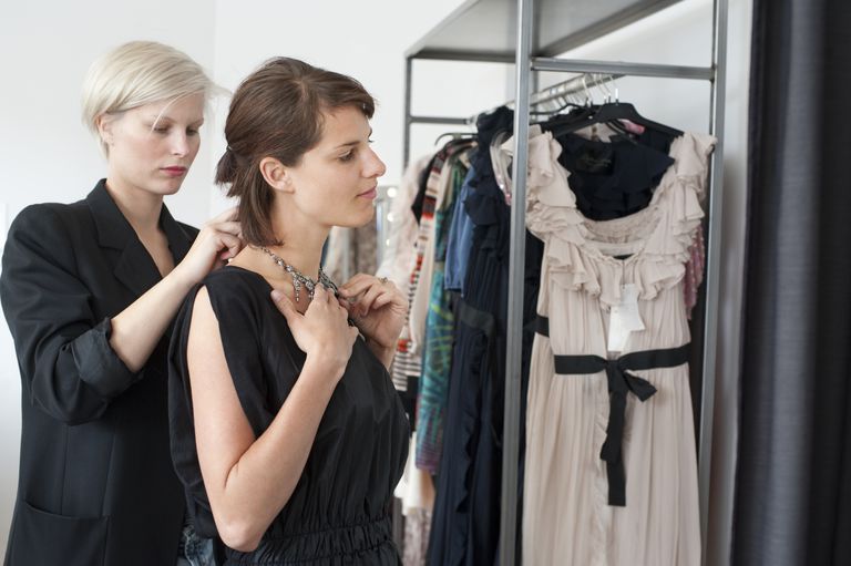 Woman tries on necklace with shop keeper's help