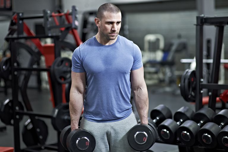 A man holding dumbbells in a gym.