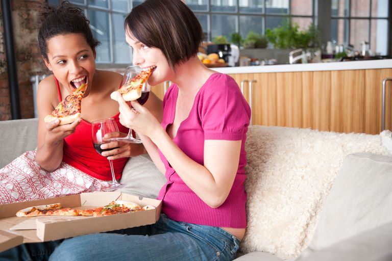 two women eating pizza and drinking wine
