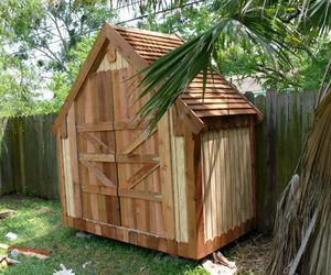 A narrow wooden shed in a backyard