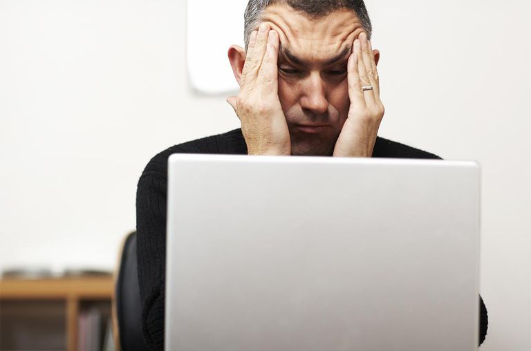 Man making faces from behind laptop