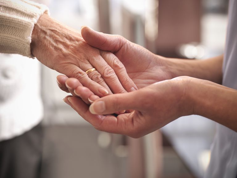 Carer holding hand of senior woman