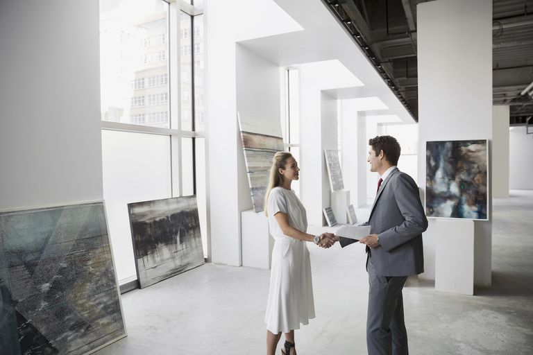 Art dealer and businessman handshaking in art gallery