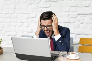 Man working at laptop expressing frustration