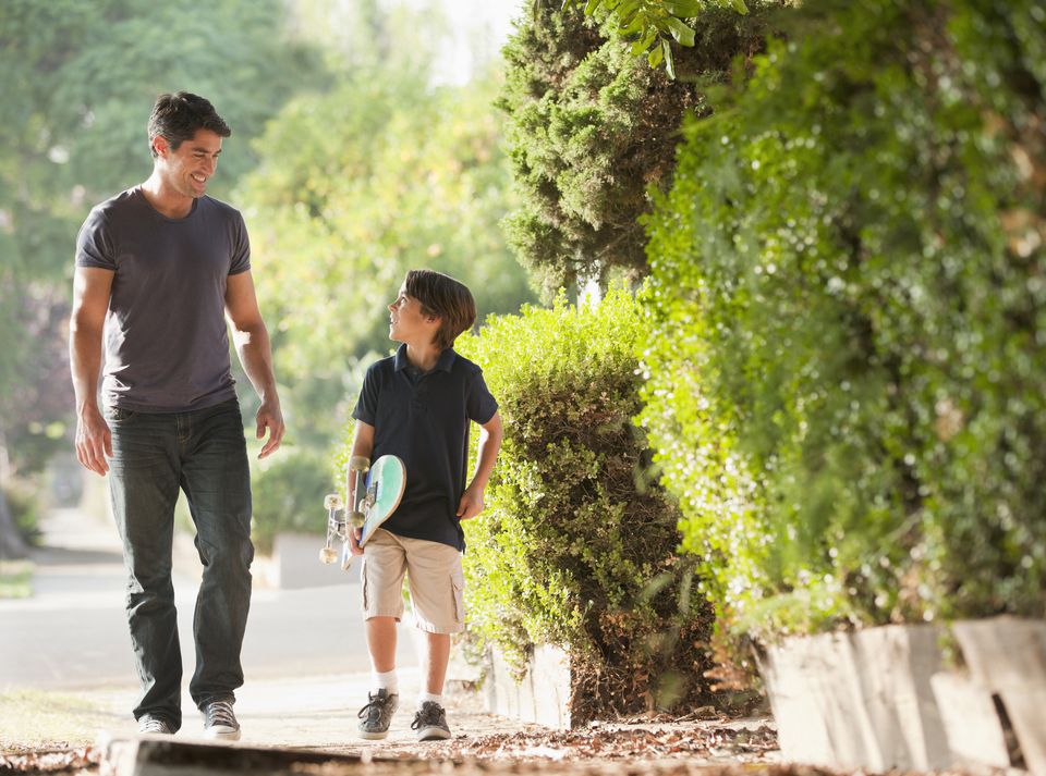 Father and son walking together on suburban street