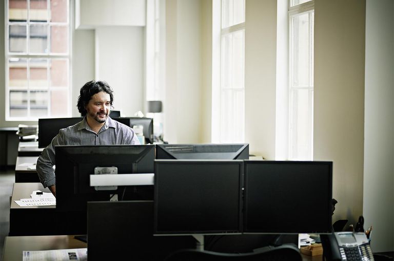 Smiling businessman in office looking at monitor