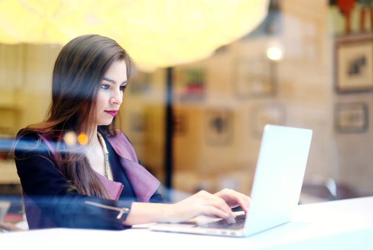 A stylish woman working on her laptop at a cafe