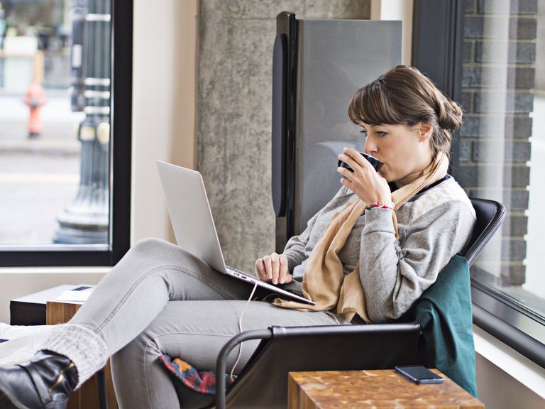 Woman drinks coffee as she checks on her laptop