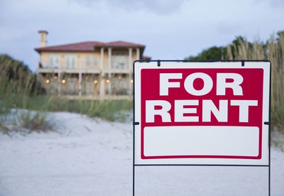 for rent sign in front of large beach house