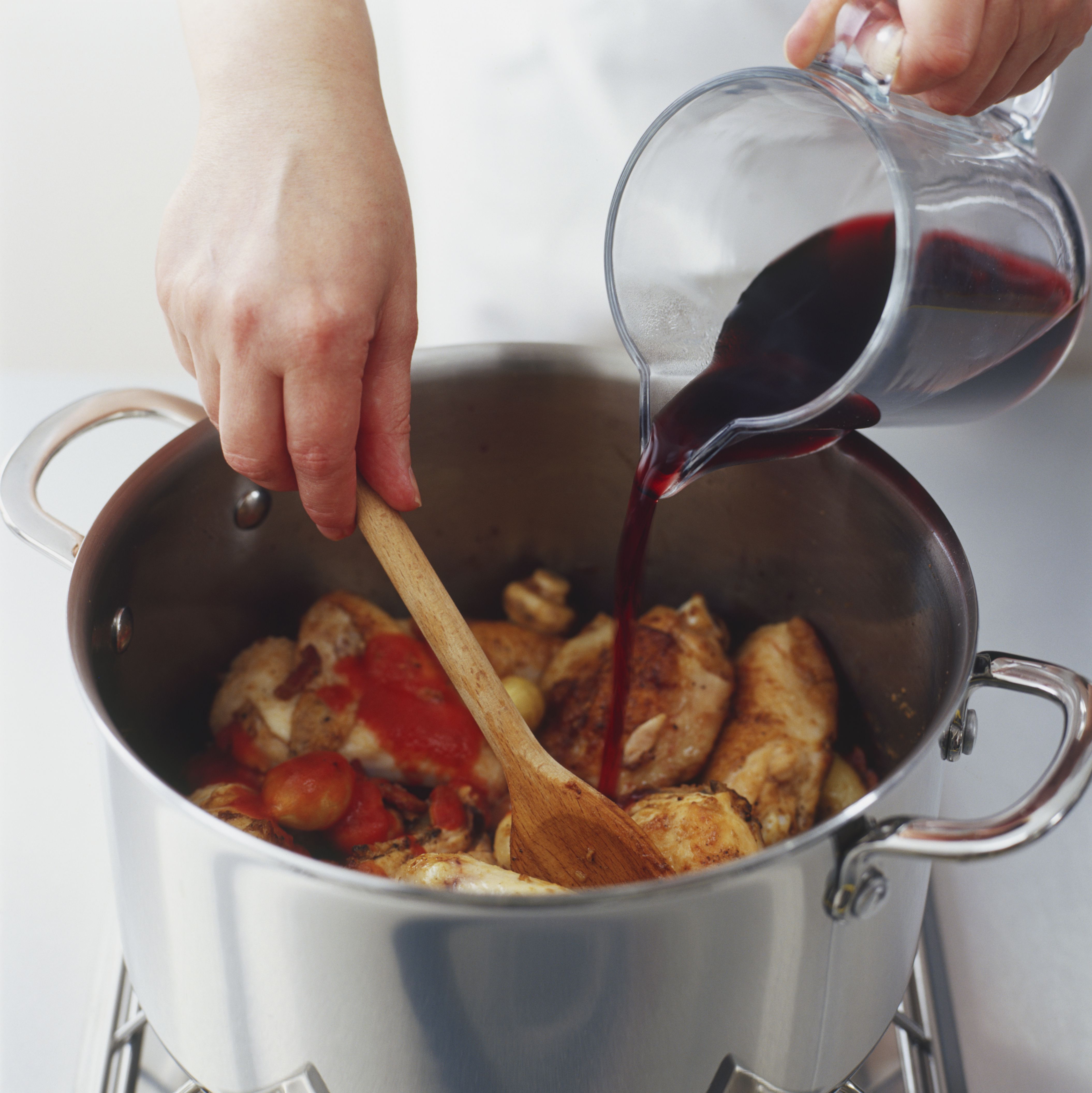stirring-mixture-of-chicken-mushrooms-onions-bacon-and-tomato-passata-cooking-in-a-pot-and-adding-red-wine-to-it-75376542-581a12dc5f9b581c0b937ef5.jpg