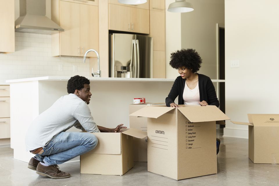 Couple unpacking cardboard box in new house