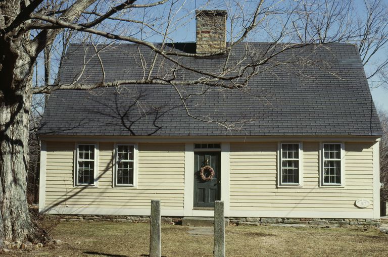 Yellow house with side gable roof, center chimney, center door, and four symmetrical double-hung windows