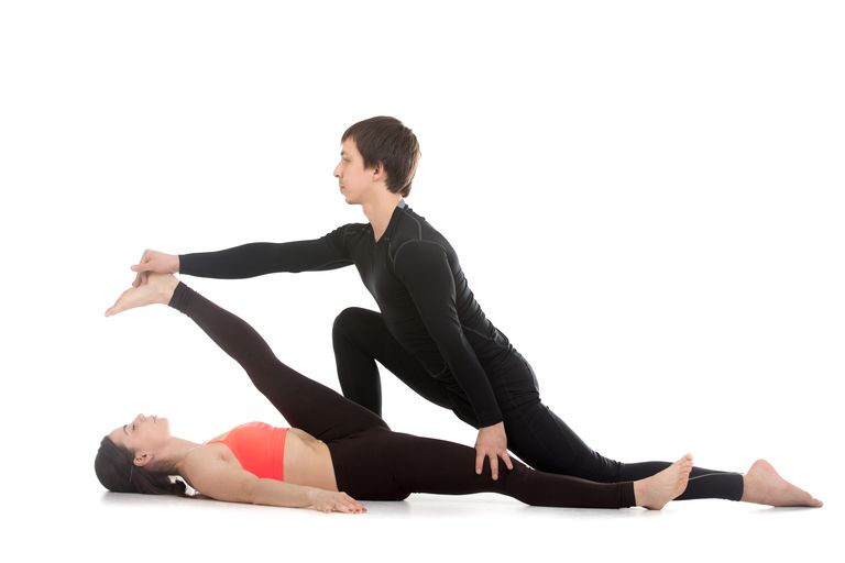 One woman helps another to further her hamstring stretch.