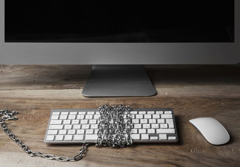 Computer monitor and keyboard, chains wrapped around keyboard