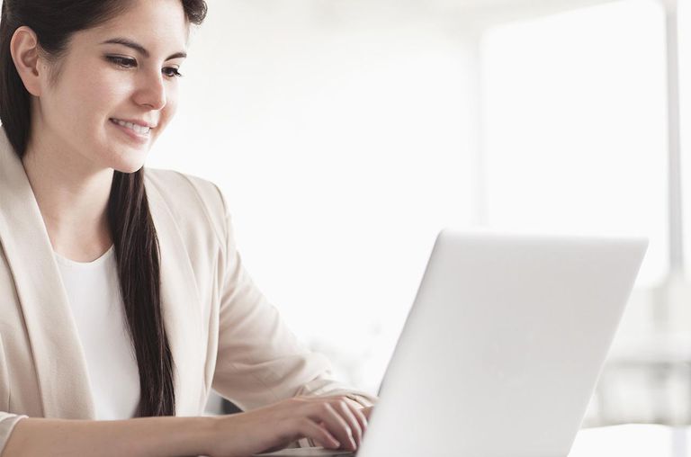 Smiling young businesswoman using her laptop