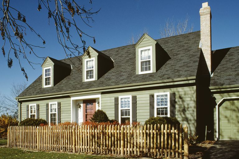 Green Cape Cod style with 3 dormers, 5 bay facade, with entryway recessed beneath a slight roof overhang