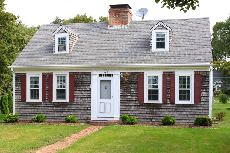 New England House with grey shingles, two small dormers without shutters, red shutters on four first-floor windows, dish antenna on roof