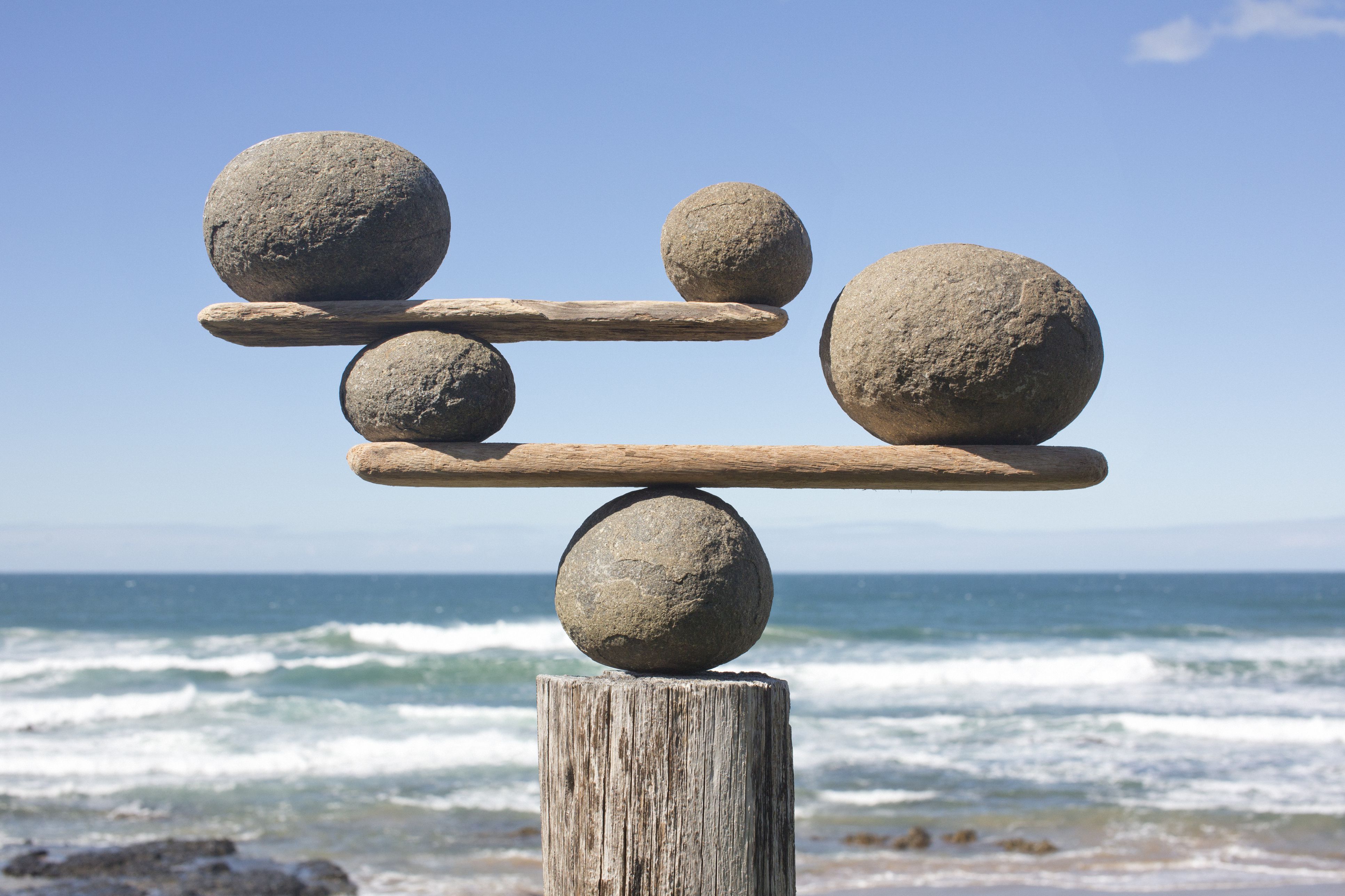 rocks-balancing-on-driftwood--sea-in-bac