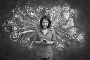 Girl on phone in front of backdrop of chalkboard with social media and online symbol sketches