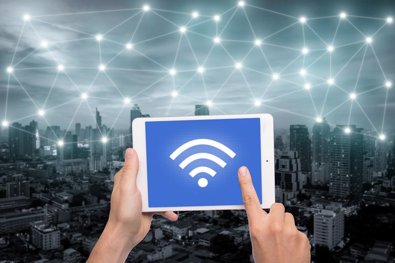 Hand holding tablet with wifi icon on city and network connection concept. Bangkok smart city and wireless communication network, abstract image visual, internet of things.